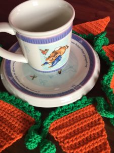 Peter Rabbit cup and plate surrounded by orange and green carrot and pea bunting