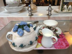 Blue Belle tea cosy on a tray in the bathroom area of Edith's House cafe
