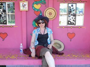 Lady in sunhat sitting in a pink hut at a Glastonbury festival