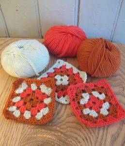 three balls of yarns and granny squares made from them