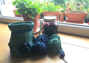 Blackberries bag in progress with jar of jam on table by a plant and window