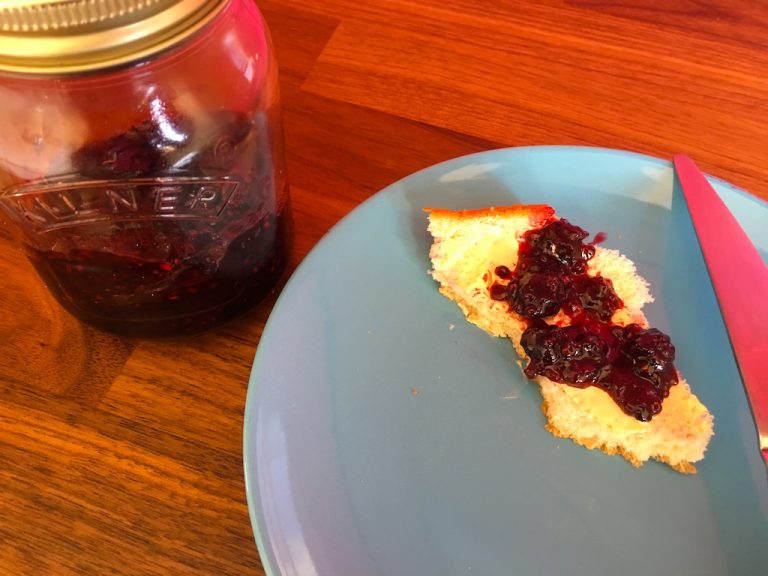 Jar of blackberry jam with bread and jam on a plate