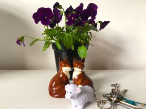 Sheep keyring and fox cruet in front of pot of violets