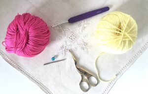 Cotton yarn crochet hook and scissors on embroidered cloth